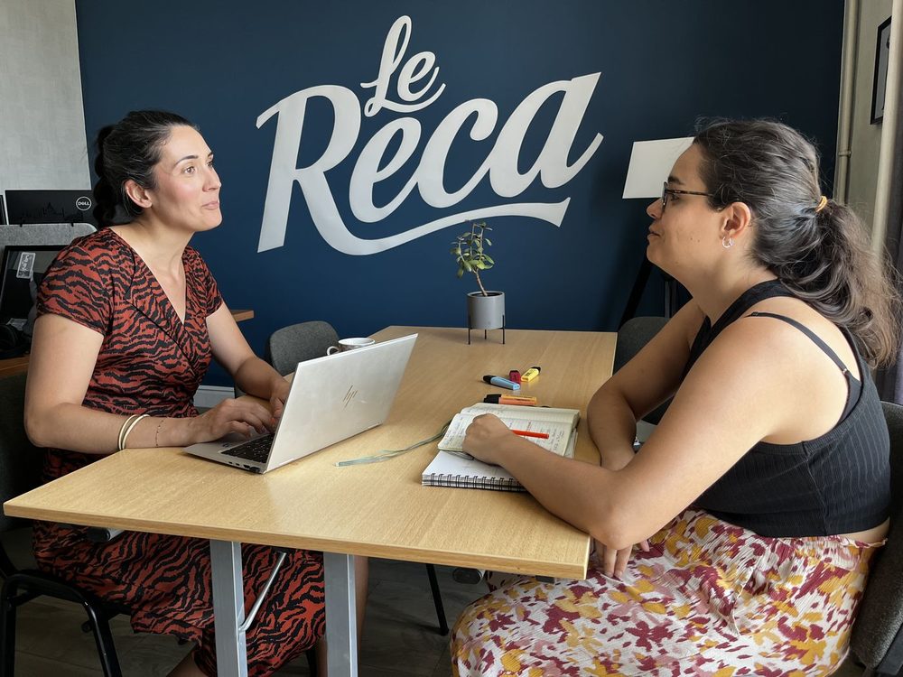 Magali Almeida en rendez-vous, à l'écoute de son interlocutrice, autour d'une table de travail.